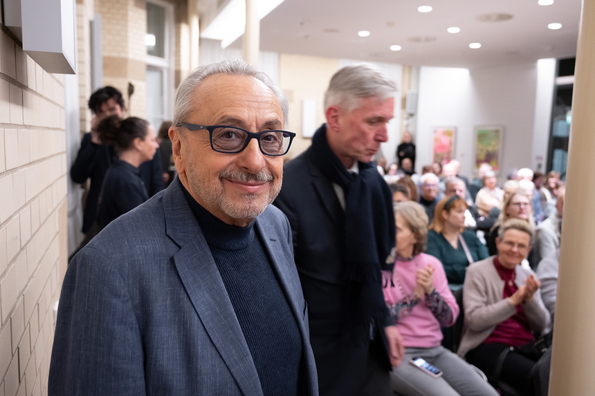 Ein Mann mit einer Brille steht in einem Veranstaltungssaal.